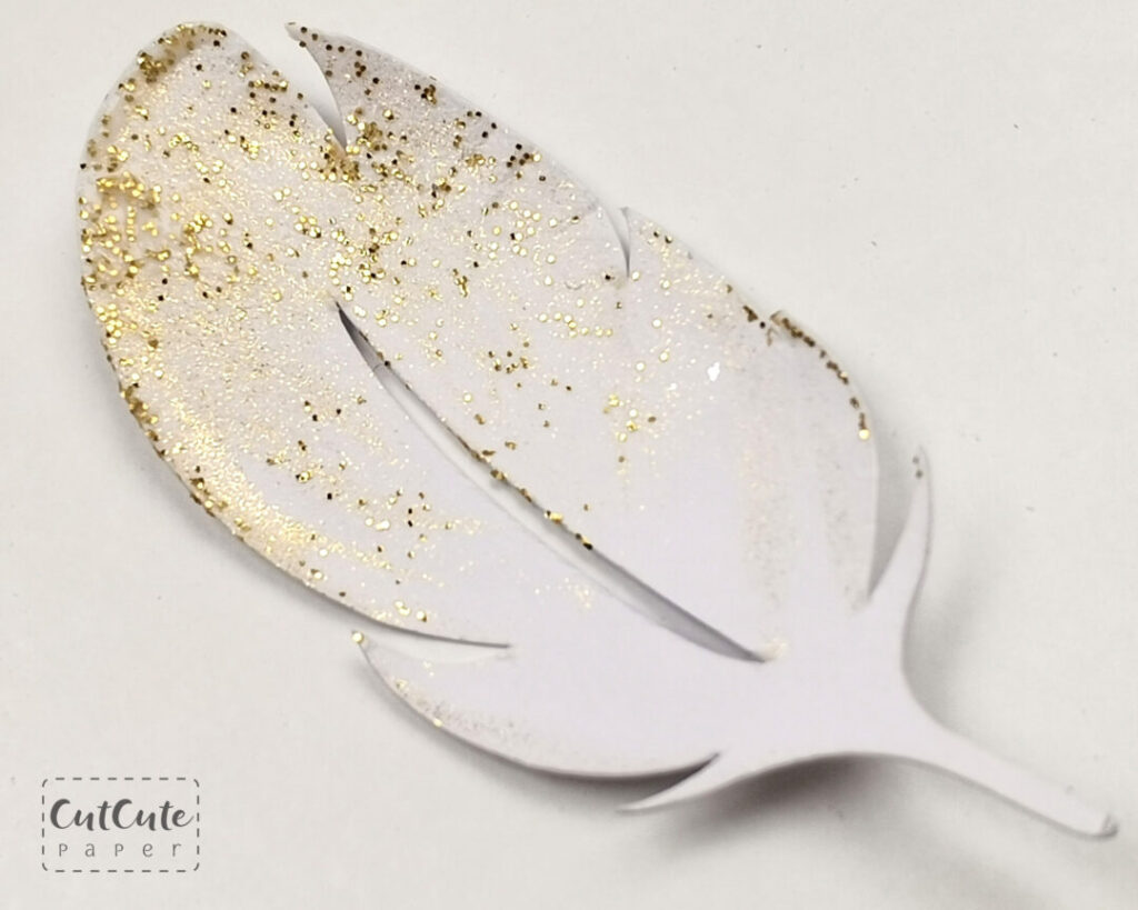 One finished white paper feather with gold